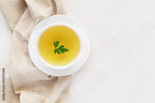 Photography Homemade chicken broth in a white plate on a white table