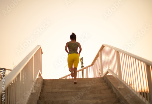 African woman jogging on the stairs. View from back.