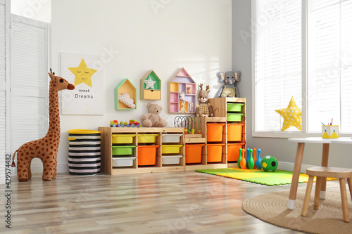 Stylish playroom interior with shelving unit and different soft toys