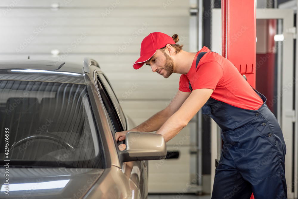 Auto mechanic standing near open window of car Auto mechanic standing near open window of car