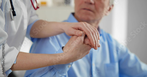 Doctor holding senior patient hands in office to support © TommyStockProject