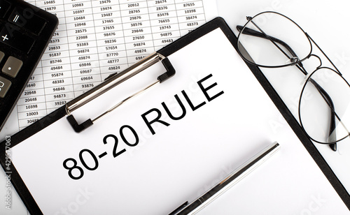 80-20 RULE text with calculator, glasses and pen on chart background. Business