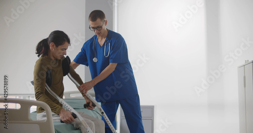 Male nurse bringing crutches to young man patient
