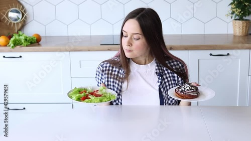 A girl on a diet cannot choose between a fresh salad and a sweet roll