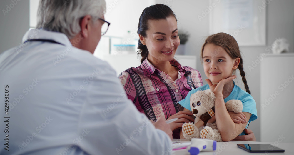 Fototapeta premium Senior pediatrician talking to mother and child at clinic office