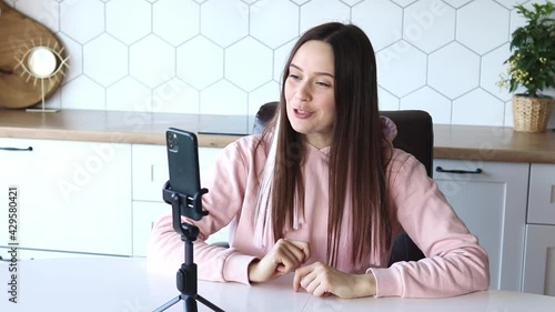 Girl blogger conducts online live broadcast at home, recording video from smartphone