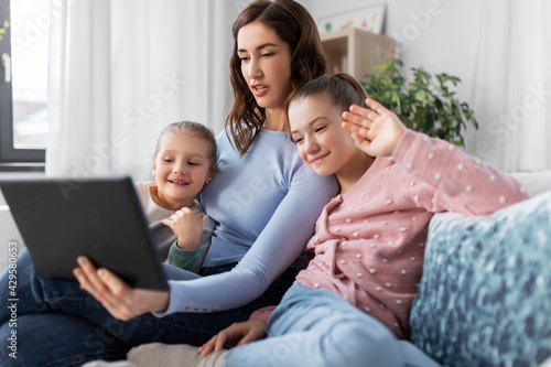 people, family and technology concept - happy mother and two daughters with tablet pc computer having video call at home