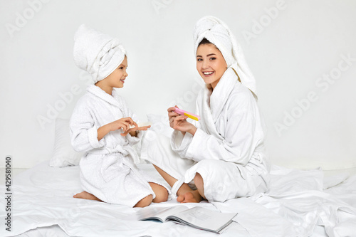 mother and daughter holding nail file and making manicure