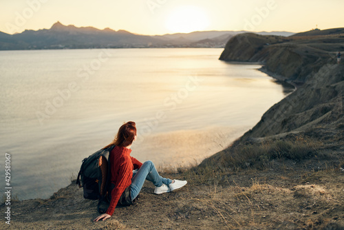 the traveler sits on the sand in the mountains and relaxes near the sea at sunset © SHOTPRIME STUDIO