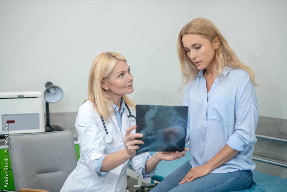 Obraz premium Doctor with x-ray and patient communicating in consultation