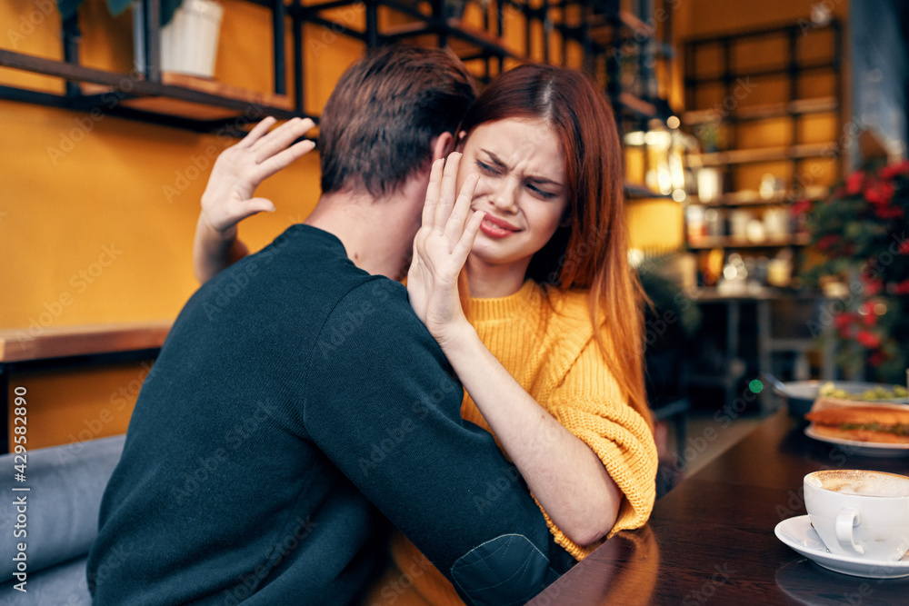 romantic woman hugs a young man in a sweater at a table in a cafe interior a couple in love romantic woman hugs a young man in a sweater at a table in a cafe interior a couple in love