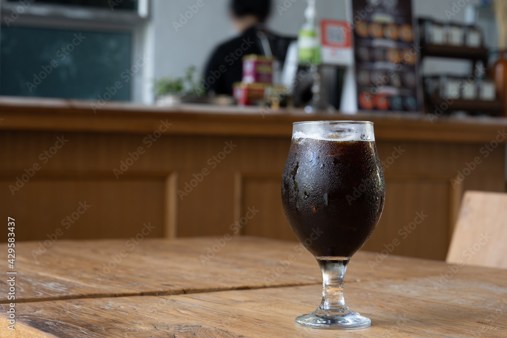 Black iced coffee glass on wooden floor