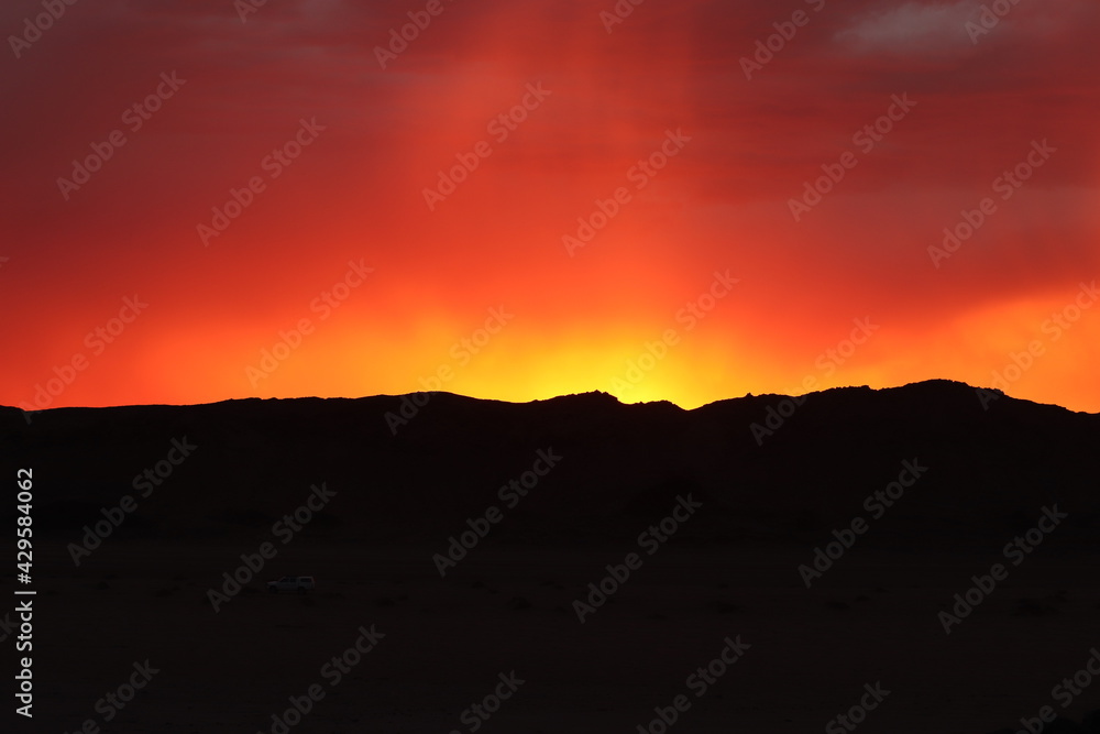Colorful sunrise over a mountain, under a stormy weather, photographed in the Namib desert in southern Namibia.