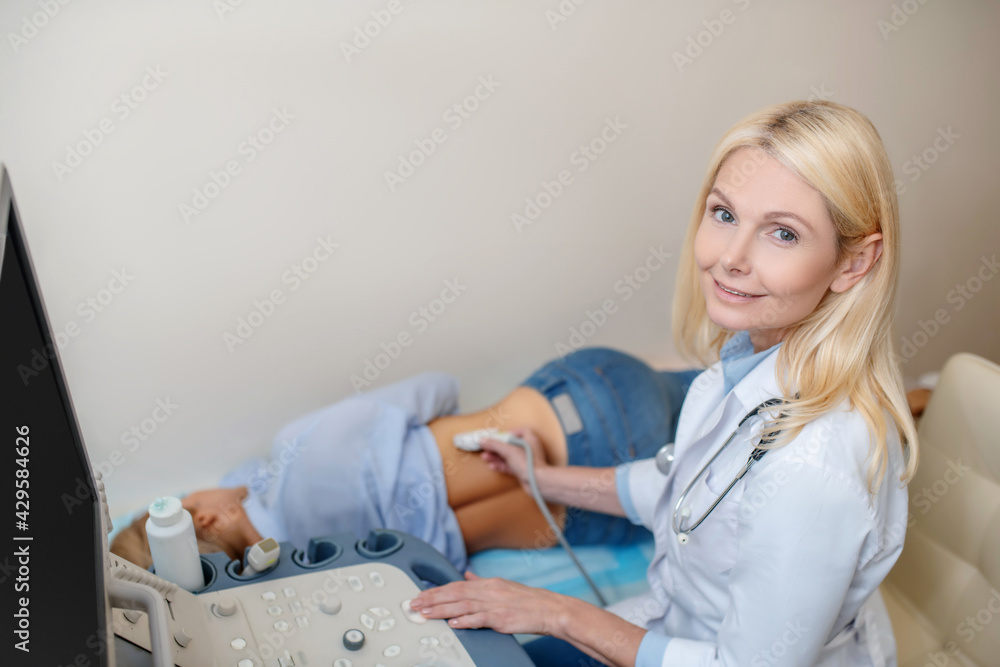 Fototapeta premium Doctor performing ultrasound examination and lying patient