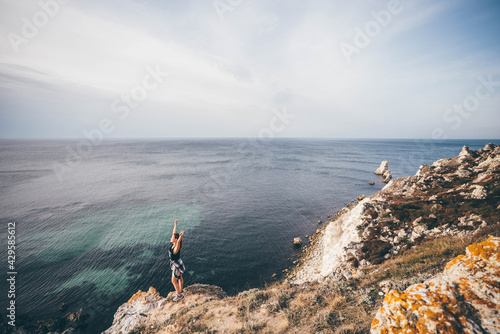 Young beautiful woman enjoying the panoramic top view of rocky beaches with cliffs.