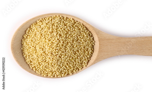 Peeled yellow millet seeds in wooden spoon isolated on white background, top view