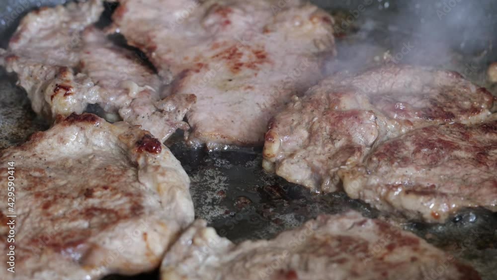 Beef steaks are fried in a pan close-up. Beef steaks are fried in a pan close-up.