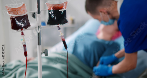 Nurse injecting syringe in female patient arm for blood transfusion