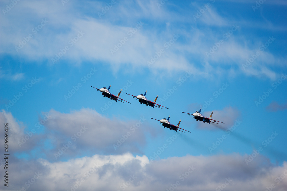 four jet planes are flying in a tight formation. dangerous aerobatics are shown at the aviation festival by pilots. military parade of modern fighter planes four jet planes are flying in a tight formation. dangerous aerobatics are shown at the aviation festival by pilots. military parade of modern fighter planes