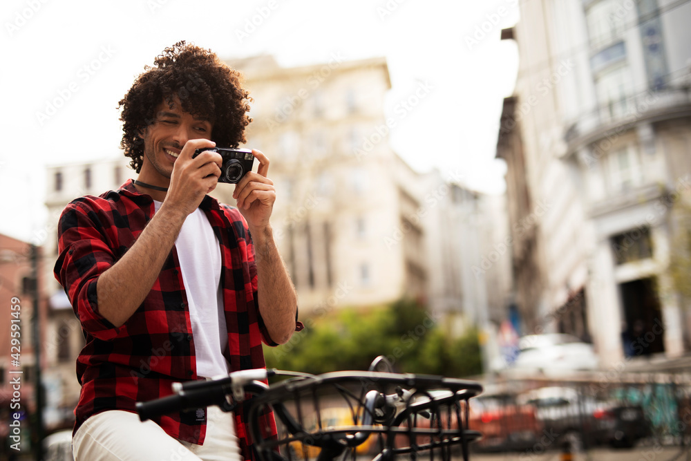 Fototapeta premium Young man traveling with camera. Handsome man traveling around the city.