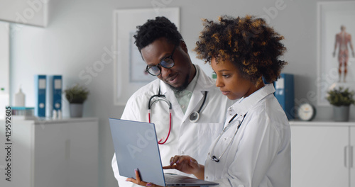 African team of doctors working on laptop in medical office