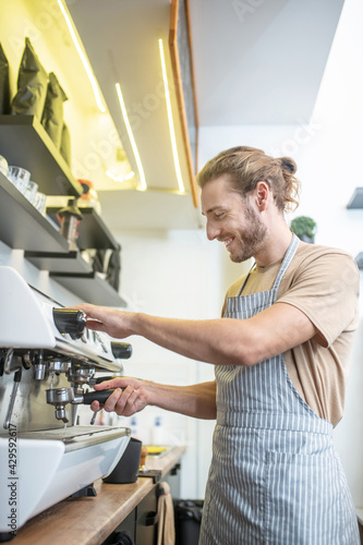 Young adult man busy near coffee machine