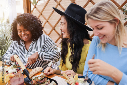 Young multiracial friends having brunch outdoors in restaurant - Focus on asian girl face
