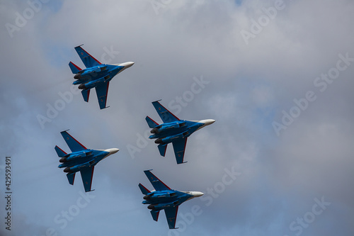 four jet planes are flying in a tight formation. dangerous aerobatics are shown at the aviation festival by pilots. military parade of modern fighter planes