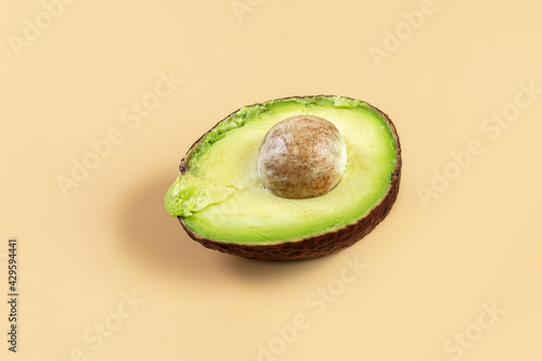 Fresh avocado on a beige background. Half an avocado with a bone. Healthy eating. Concept.