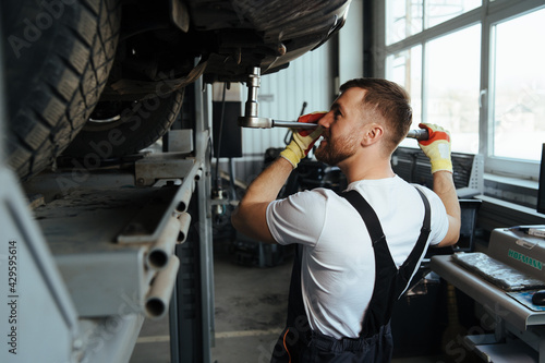 Professional auto mechanic working on the undercarriage of a car diligence
