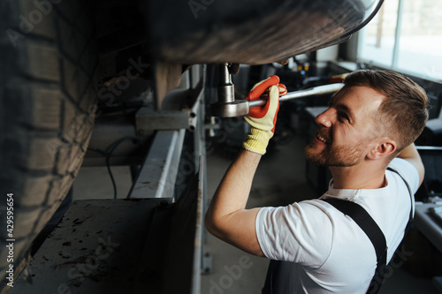 Professional auto mechanic working on the undercarriage of a car diligence