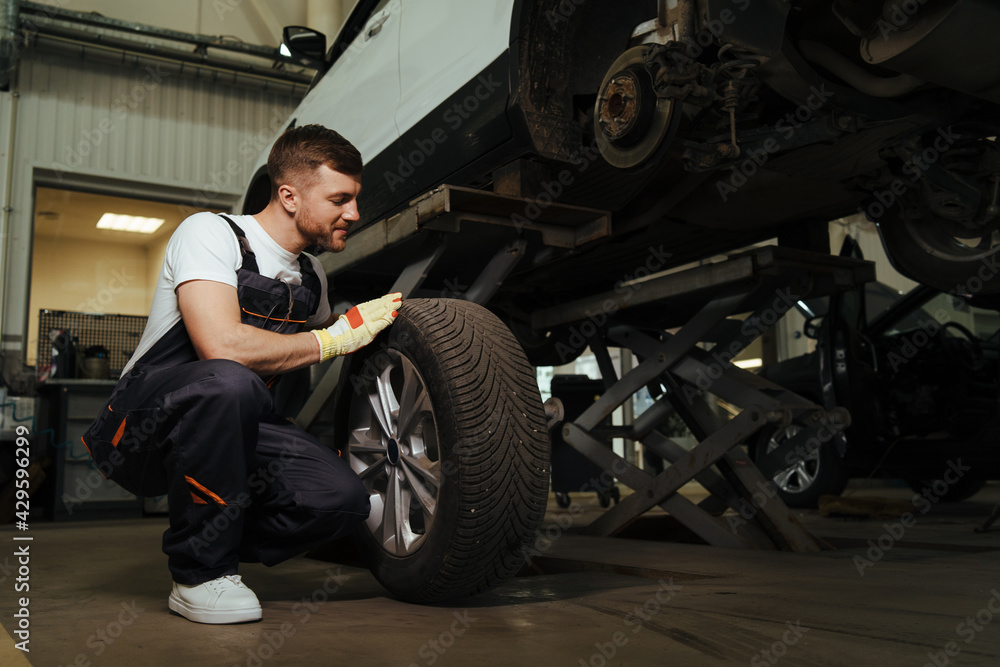 Mechanic changing a wheel and tire of modern car in workshop Mechanic changing a wheel and tire of modern car in workshop