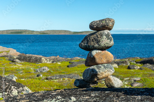 A pyramid of stones on the background of the White Sea coast on a sunny day. The concept of life balance, harmony and meditation. A memorable sign in the journey.