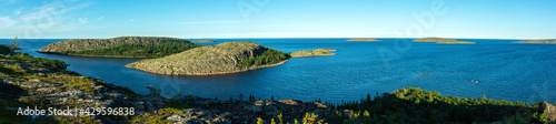 Panoramic view from a high point of the sea, the island, the rocky coast and the horizon line on a clear sunny day. White Sea, archipelago Kuzova, Russia. Concept of travel in the northern latitudes.