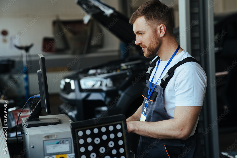 Car mechanic installing sensor  adjustment and automobile wheel - obrazy, fototapety, plakaty 