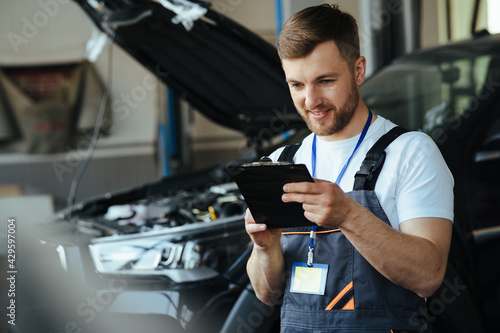 Mechanic engineer taking a note on clipboard for examining a vehicle