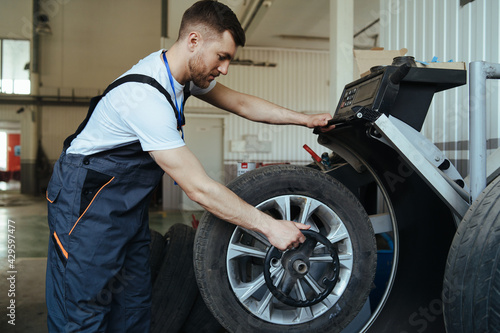 Mechanic balancing  car wheel on balancer in workshop