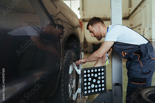 Car mechanic installing sensor  adjustment and automobile wheel