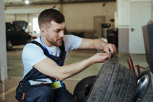 Mechanic measuring depth of car tires in auto repair shop © taras.chaban