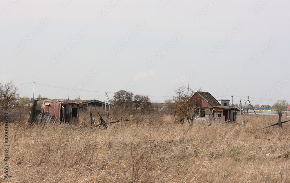 Abandoned small country houses in a field among dry grass