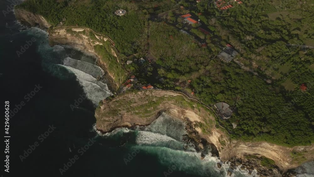 Aerial drone view of crashing waves in blue ocean water onto huge cliffs at Uluwatu Bali Indonesia during sunset on coastline. Wild beaches. Pura Luhur Uluwatu temple. High quality 4k footage Aerial drone view of crashing waves in blue ocean water onto huge cliffs at Uluwatu Bali Indonesia during sunset on coastline. Wild beaches. Pura Luhur Uluwatu temple. High quality 4k footage