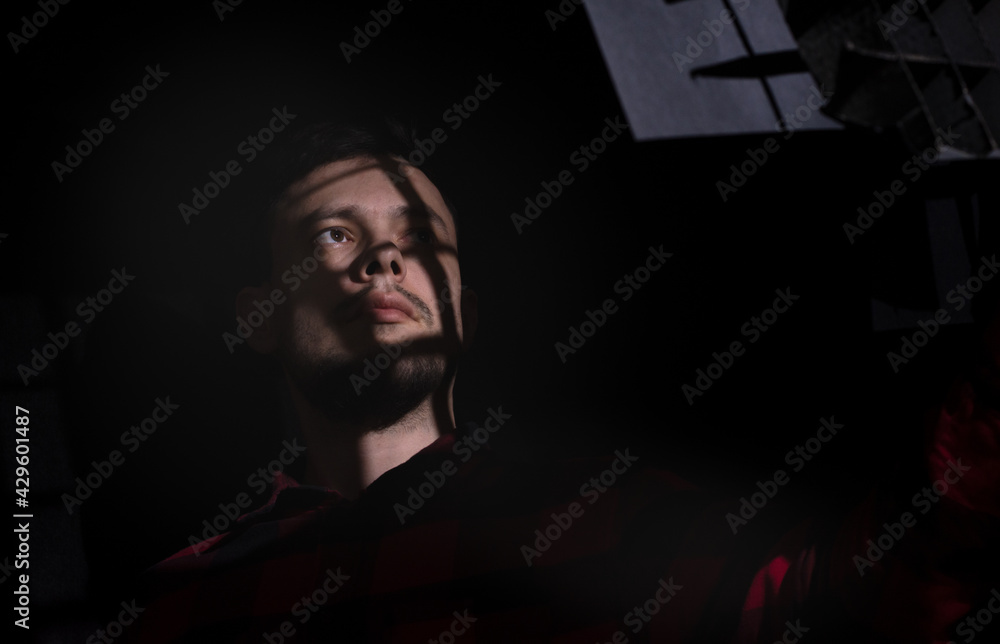 Young dark-haired unshaven man looks at the light through the bars, dreams of freedom, on a dark background. The concept of freedom Young dark-haired unshaven man looks at the light through the bars, dreams of freedom, on a dark background. The concept of freedom