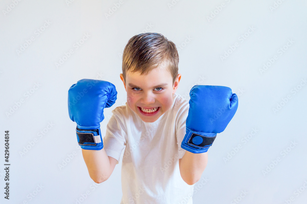 A boy in boxing gloves stands in a fighting stance. Sports and self-defense. A boy in boxing gloves stands in a fighting stance. Sports and self-defense.