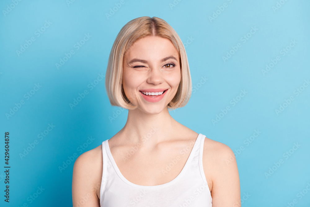 Close-up portrait of charming cheerful blond girl winking flirting isolated over vibrant blue color background Close-up portrait of charming cheerful blond girl winking flirting isolated over vibrant blue color background