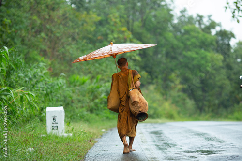 buddhist monk walking on the road under the rain