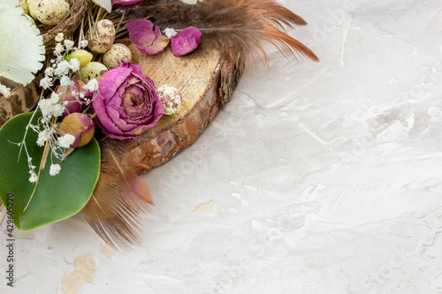 Easter composition with eggs, feathers and flowers on grey background