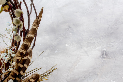 Easter composition with eggs, feathers and flowers on grey background