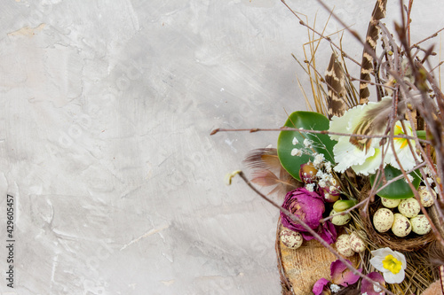 Easter composition with eggs, feathers and flowers on grey background