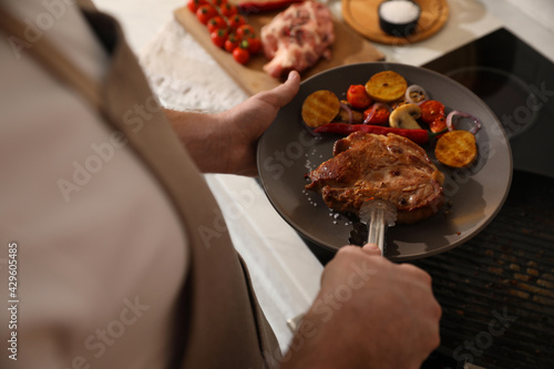 Man with tasty meat and vegetables cooked on frying pan, above view