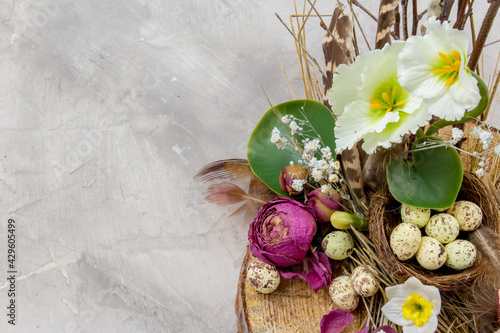 Easter composition with eggs, feathers and flowers on grey background